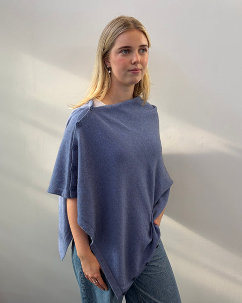 Woman wearing a blue poncho against a plain background