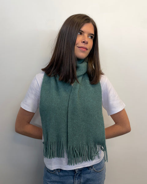 Person wearing a teal scarf against a plain background
