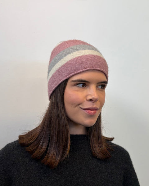 Person wearing a pink striped beanie with a plain background