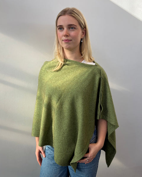Woman wearing a green poncho against a plain background