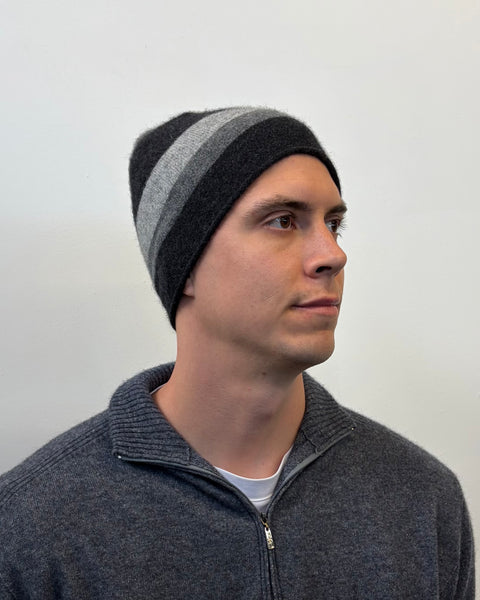 Man wearing a gray and black striped beanie against a plain background
