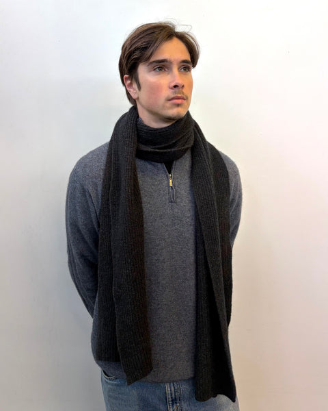 Man wearing a dark gray scarf and gray sweater against a white background