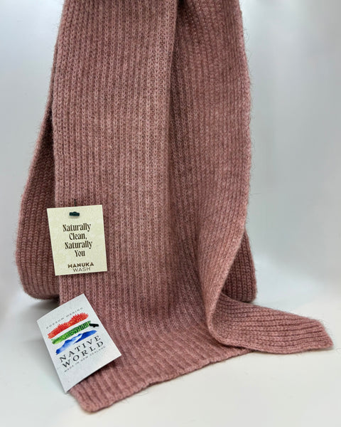 Pink knitted scarf with a tag on a white background