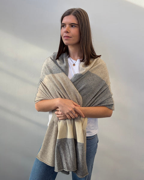 Woman wearing a beige and gray striped shawl against a plain background