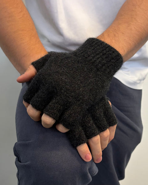 Dark grey fingerless gloves worn by a person on a plain background