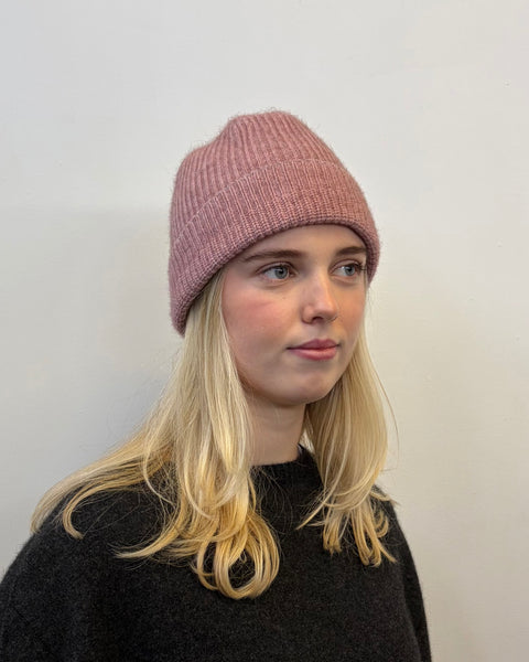 Person wearing a pink beanie against a plain background