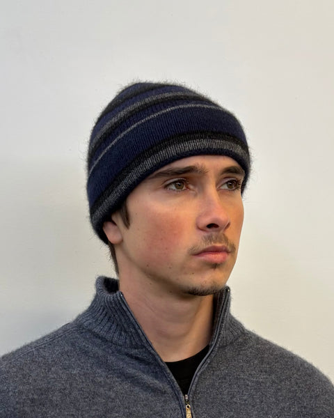 Man wearing a striped beanie and gray sweater against a plain background