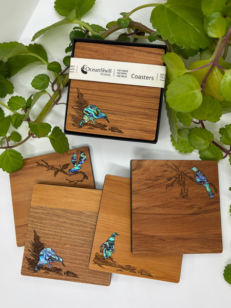 Set of wooden coasters with New Zealand native bird designs on a leafy background
