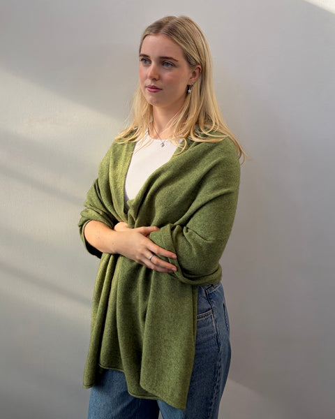 Woman wearing a green shawl over a white shirt with a plain background