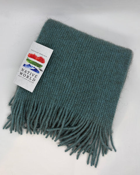 Teal scarf with fringes and a 'Native World' tag on a white background