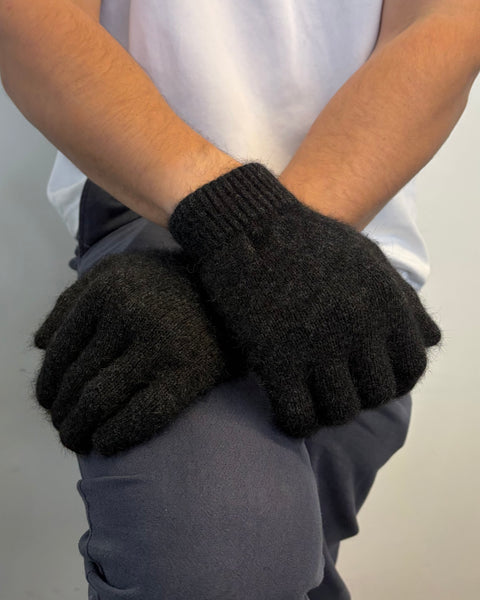Person wearing dark grey gloves with a plain background