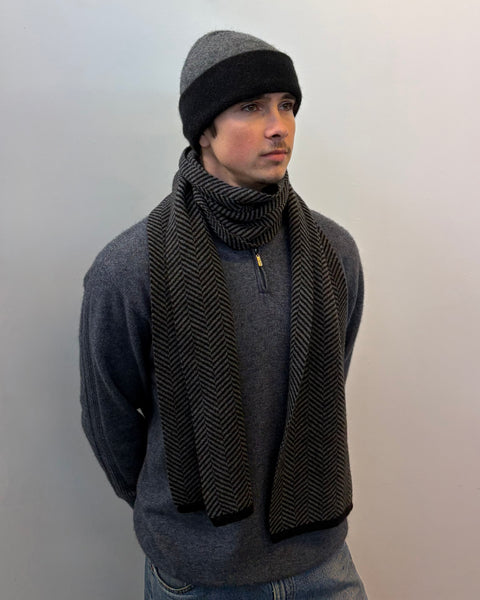 Man wearing grey scarf and beanie against a plain background