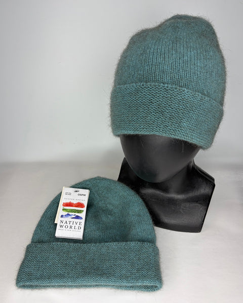 Two teal knit hats on a mannequin head and flat surface with a Native World label.