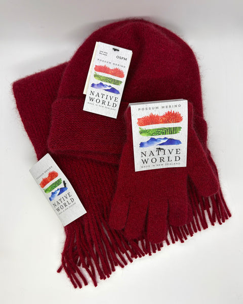 Red knitted beanie, scarf and gloves set with 'Native World' tags against a white background.