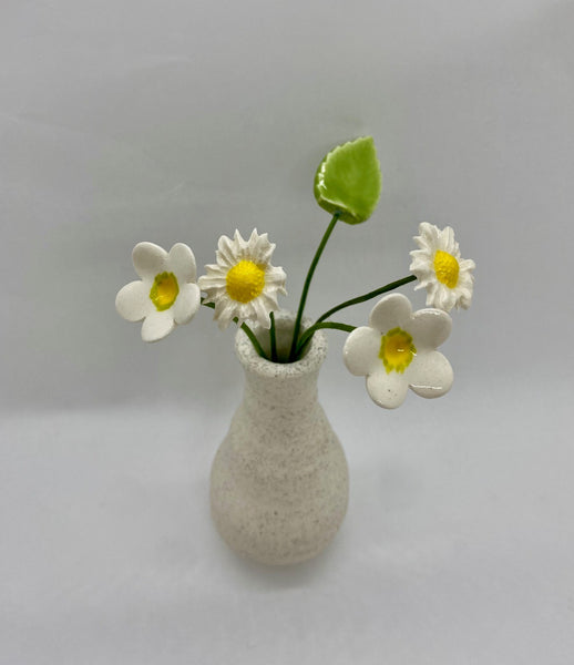 A selection of ceramic flowers displayed in a white speckled vase.