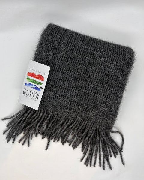 Gray knitted scarf with fringes and a 'Native World' tag on a white background