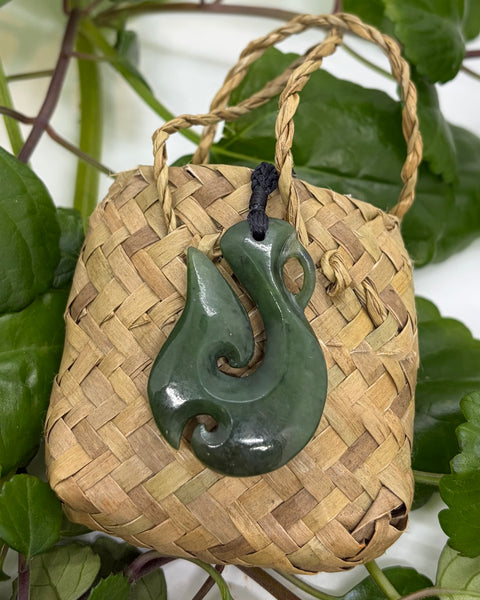 Greenstone fish hook pendant on a woven flax bag