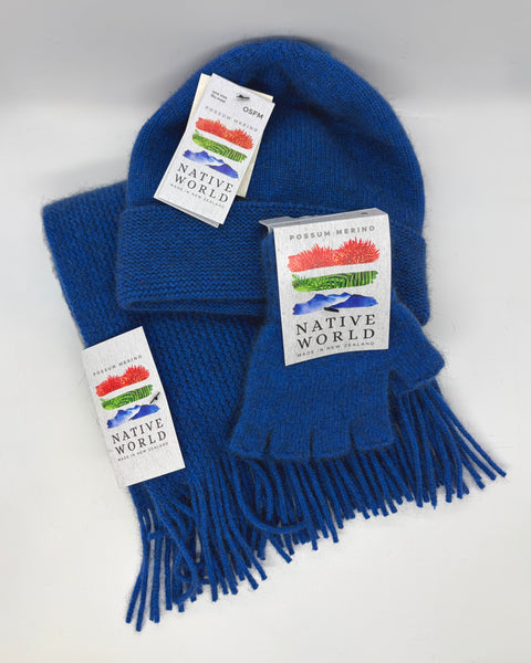 Blue knit beanie, scarf, and fingerless gloves set with 'Native World' tags on a white background.