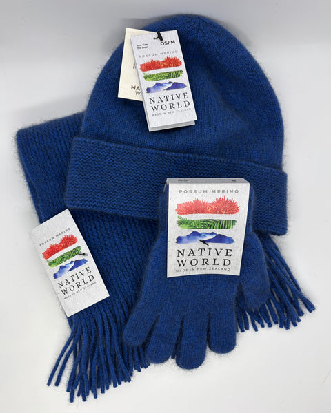 Blue knit beanie, scarf and gloves set with 'Native World' tags against a white background