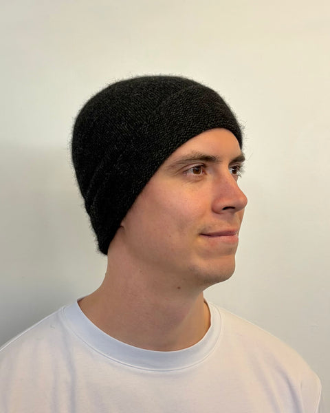 Person wearing a charcoal knit beanie against a plain background