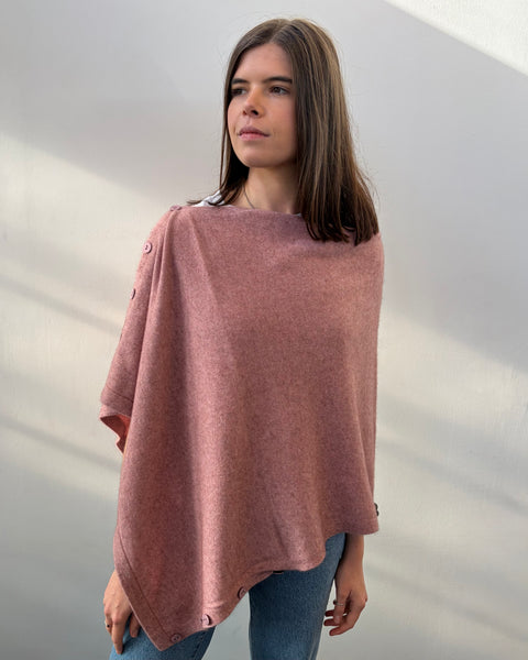 Woman wearing a pink poncho against a neutral background