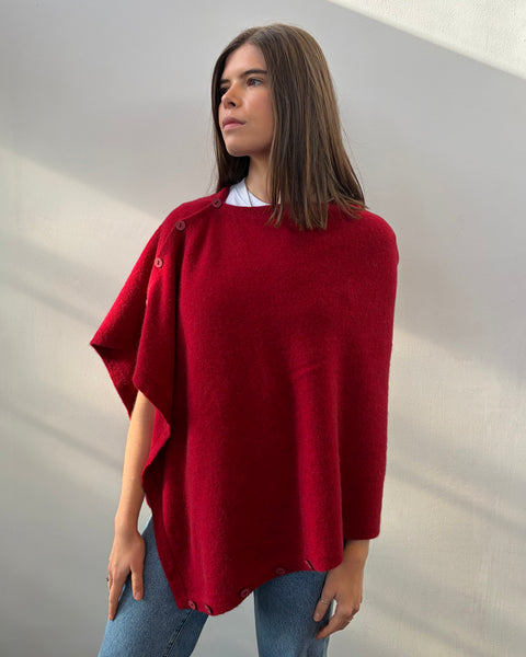 Woman wearing a red poncho against a plain background