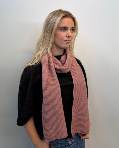 Woman wearing a pink scarf against a plain background