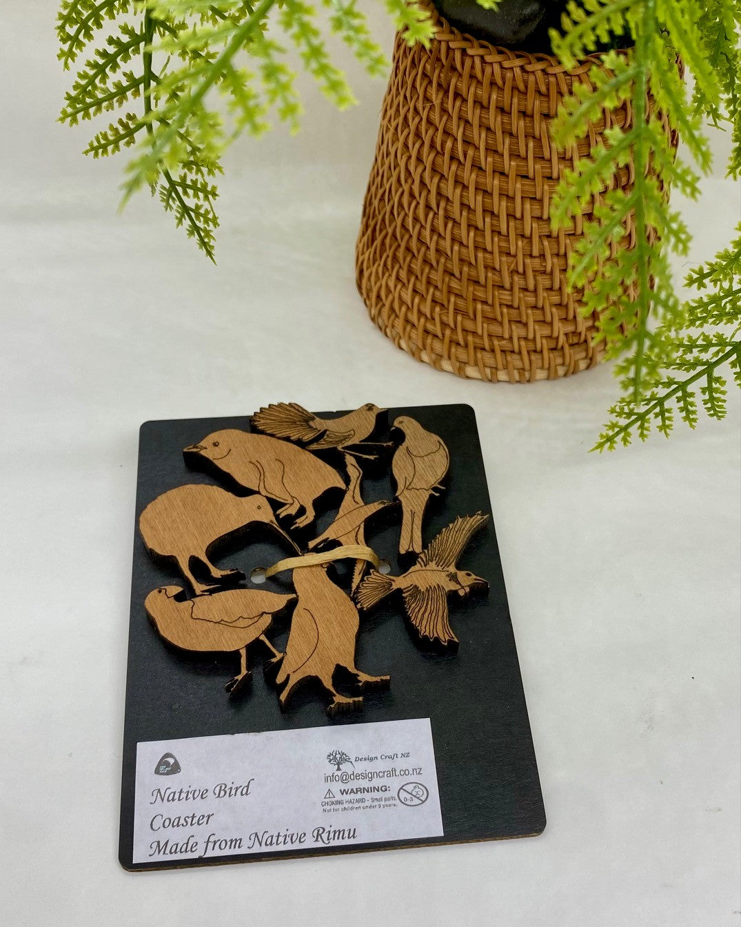 Wooden coaster with bird designs on a black base.