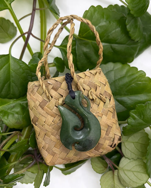 Greenstone fish hook pendant on a woven flax bag