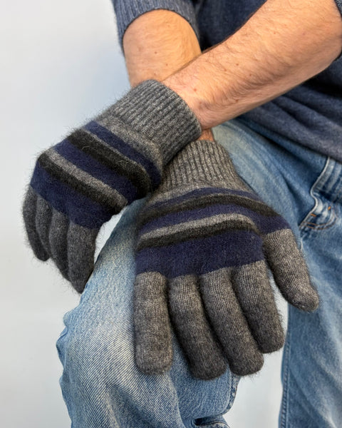 Pair of gray and navy striped gloves worn by a person wearing jeans.