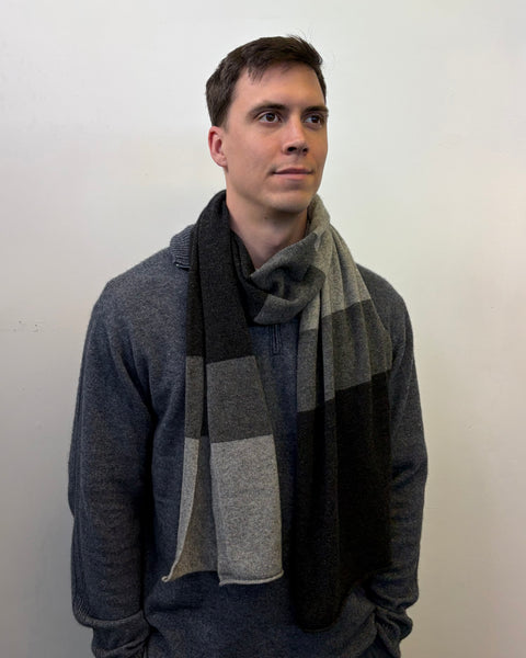 Man wearing a grey and black striped scarf against a plain background