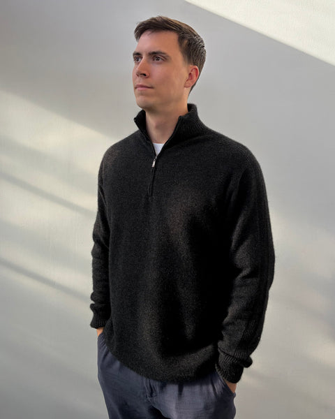 Man wearing a dark grey sweater against a plain background