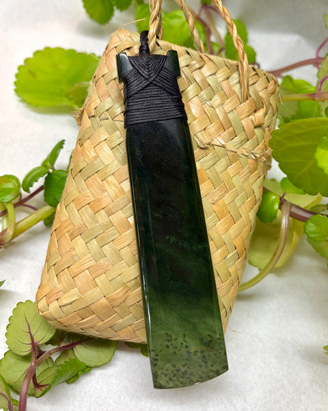 Greenstone pendant on a woven flax bag