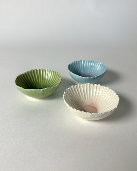 Three unique small ceramic handcrafted gerbera flower bowls in green, blue, or pink. Made in New Zealand by Muddy Fingers and sold individually.
