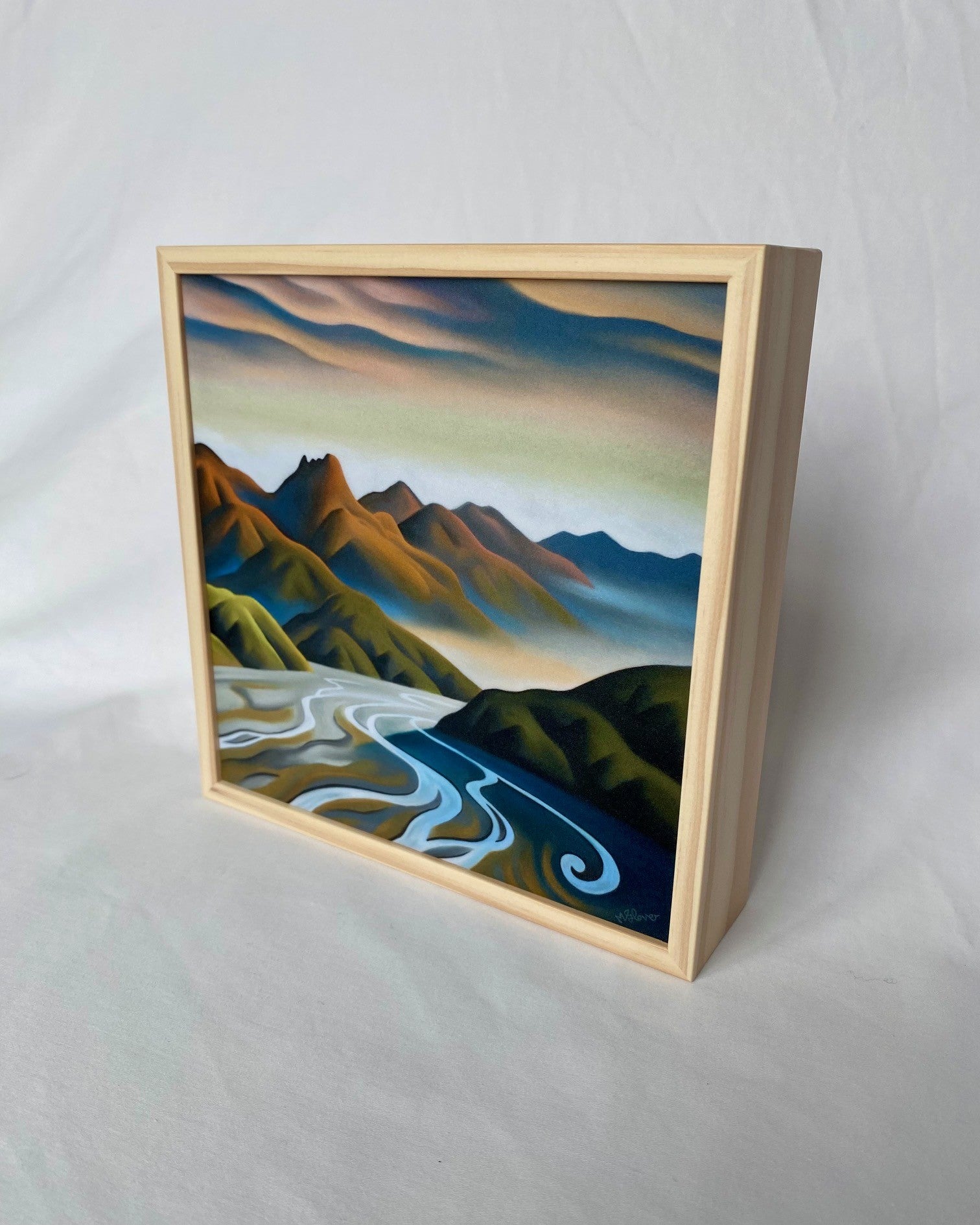 Framed artwork of a mountain landscape with a river on a plain background