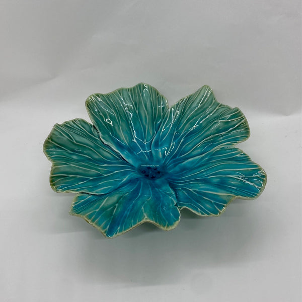 Turquoise ceramic flower-shaped dish on a white background