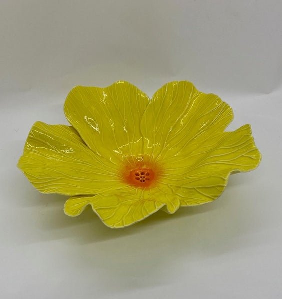 Ceramic yellow flower-shaped dish on a white background