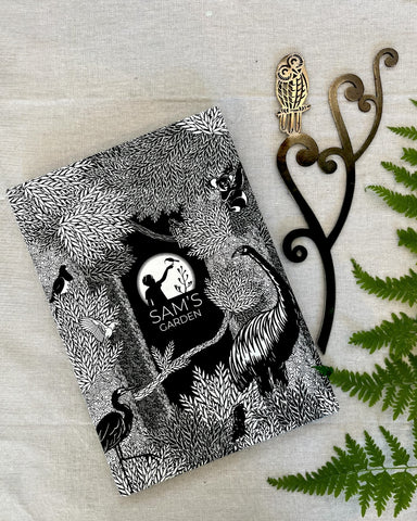 A steel garden sculpture of the NZ native Morepork Owl perched on unfurling silver fern fronds with a decorated gift box by 'Sam's Garden'