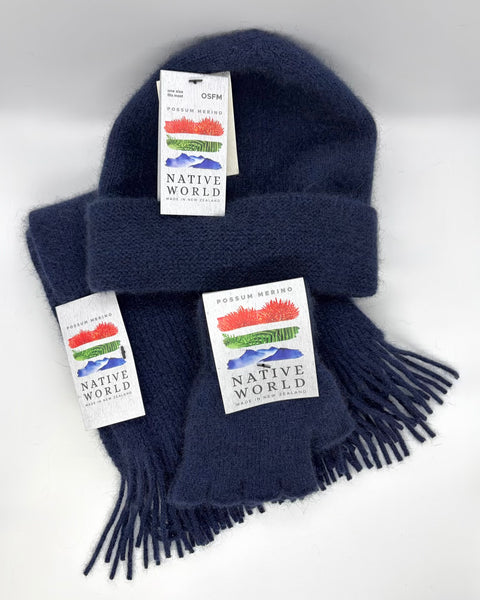 Navy blue knit beanie, scarf and fingerless gloves set with 'Native World' tags on a white background.