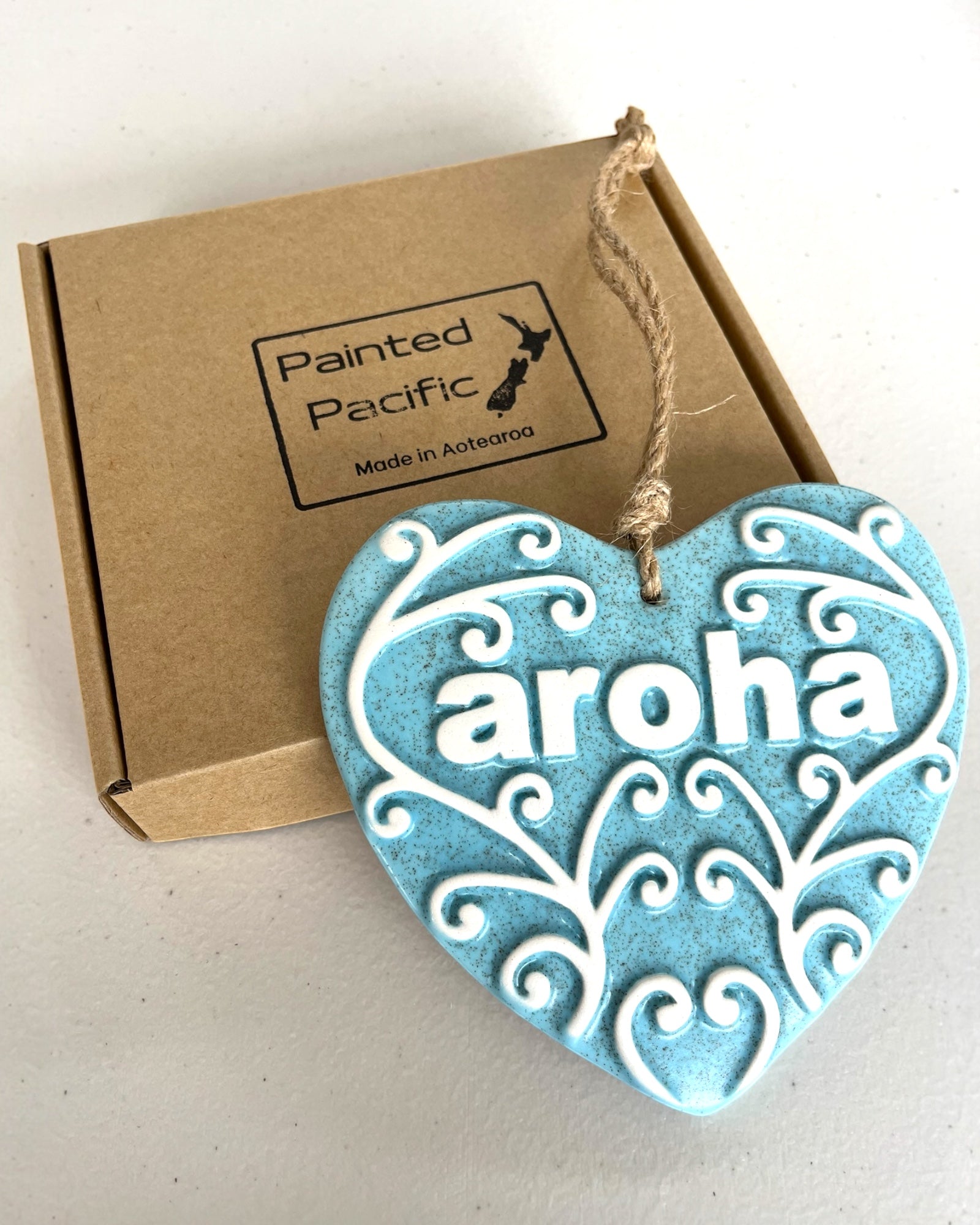 Light Blue Ceramic Heart with Koru design and the word Aroha, meaning love, with a twine loop for hanging and its own gift box. Made in New Zealand by Painted Pacific Pottery.