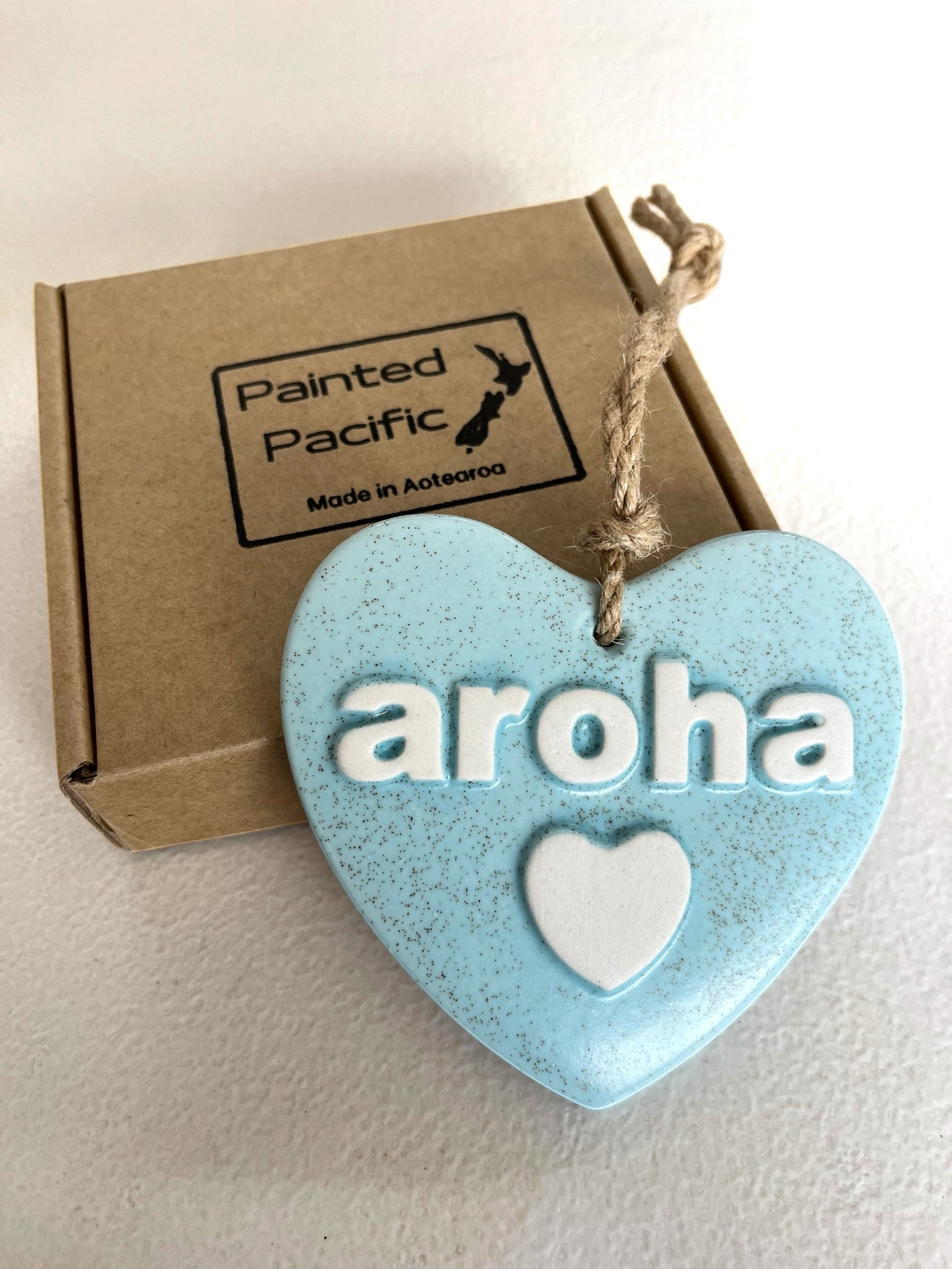 Light Blue Ceramic Heart with the word Aroha, meaning love. With a twine loop for hanging and its own gift box. Made in New Zealand by Painted Pacific Pottery