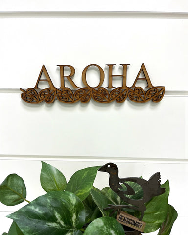 A New Zealand Made wooden sign that says 'Aroha' (Love) underlined with traditional Maori art designs.