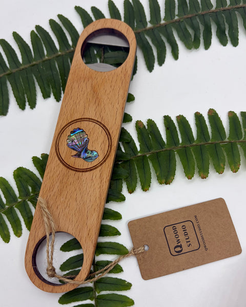 Wooden bottle opener with fantail design on a leafy background