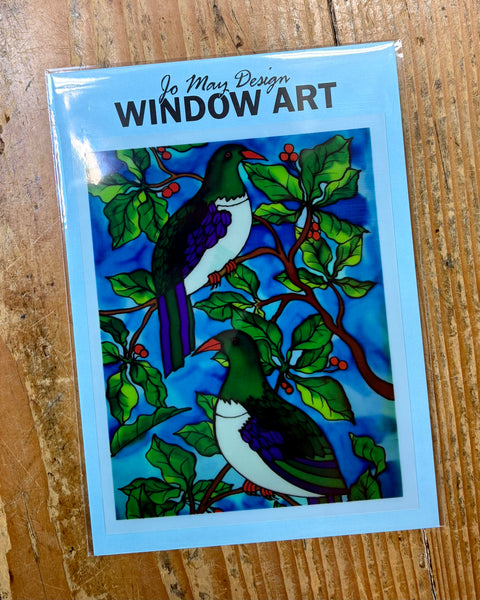 Window art decal with kereru birds on a wooden surface