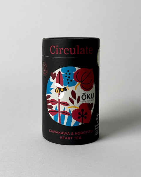 A cylindrical tin of OKU brand tea bags with a colorful label featuring floral patterns and the text 'Circulate'.
