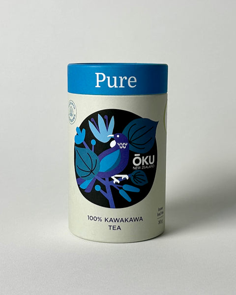 A cylindrical container of OKU Pure loose leaf tea with a label featuring a blue design and text indicating it is 100% Kawakawa tea.