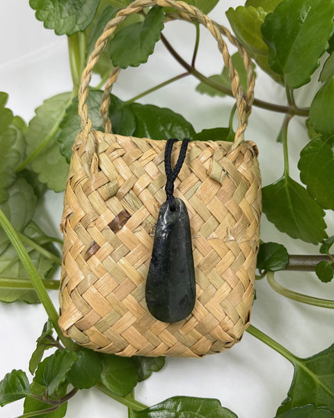 Greenstone teardrop pendant on a woven flax bag