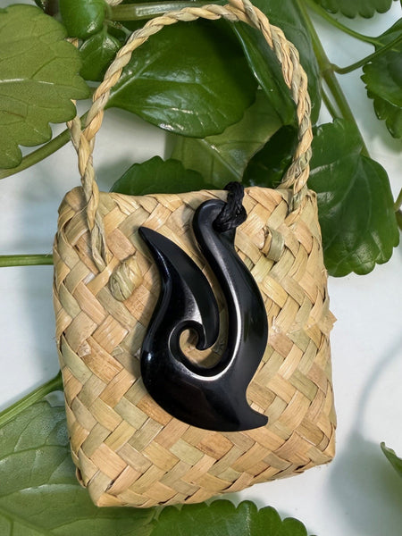Greenstone fish hook pendant on a woven flax bag