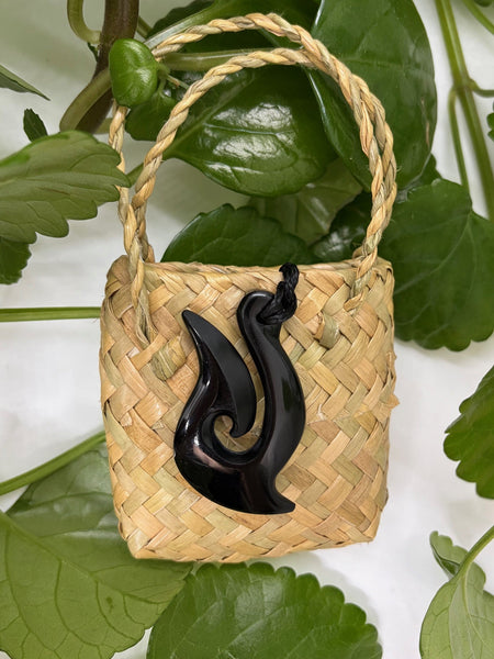 Greenstone fish hook pendant on a woven flax bag