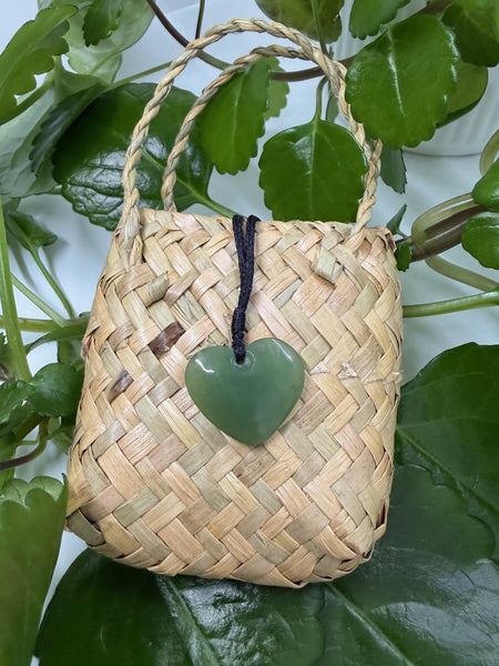 A heart-shaped greenstone pendant on a woven flax bag.